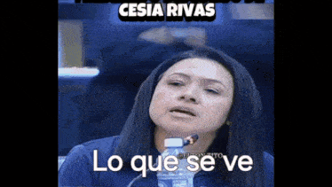 a woman is holding a bottle of water in front of a microphone and says lo que se ve .