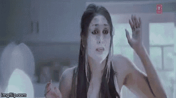 a woman with a white mask on her face is looking at herself in a mirror .