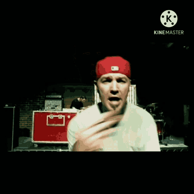 a man wearing a red hat and a white shirt is standing on a stage .