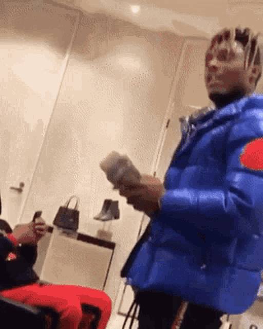 a man in a blue jacket is holding a bunch of money in his hands .