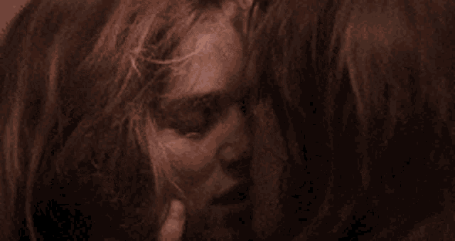 a close up of two women kissing with their eyes closed .