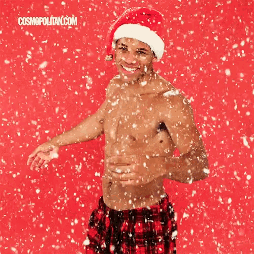 a shirtless man wearing a santa hat is standing in the snow ..