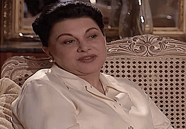 a woman in a white shirt sits in a wicker chair