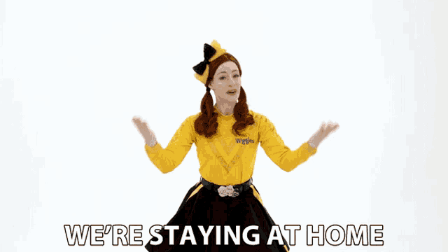 a woman in a yellow shirt and black skirt is dancing with the words we 're staying at home behind her