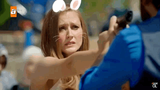 a woman wearing bunny ears is being held by a man with a gun