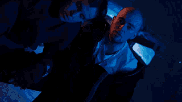 two men standing next to each other in a dark room