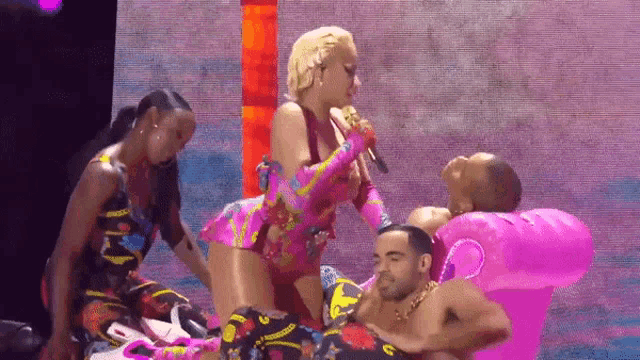 a woman is singing into a microphone while a man is laying on an inflatable chair .
