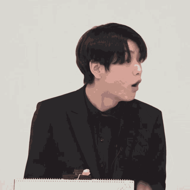 a man in a black suit is making a face
