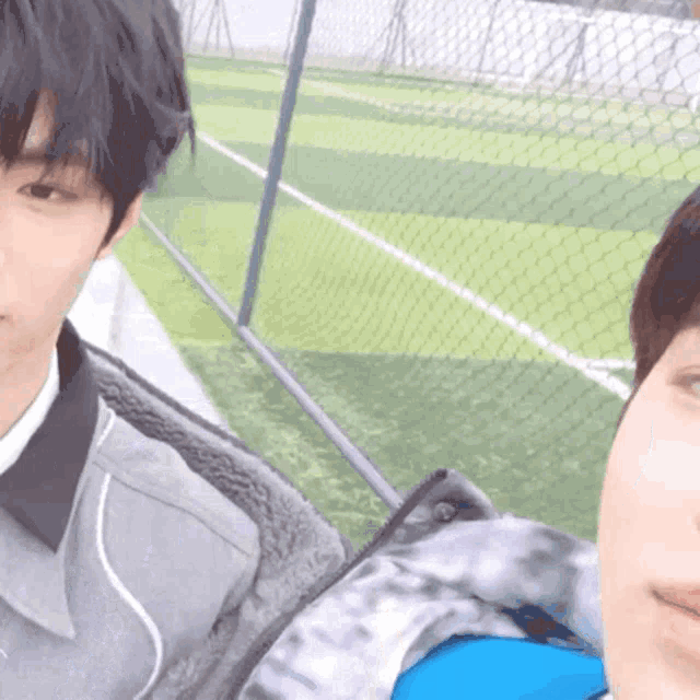 two young men are taking a selfie in front of a fence