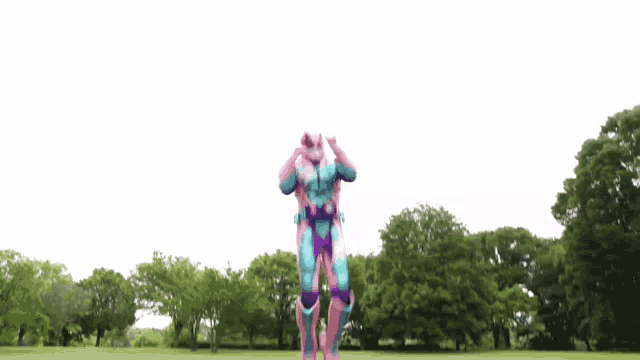 a person in a superhero costume is jumping in the air in a park