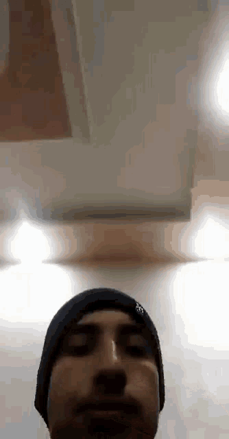 a man wearing a black beanie is looking at the camera in a room .
