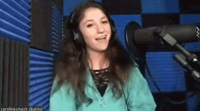 a young girl wearing headphones is singing into a microphone .