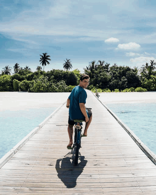 a man is riding a bike on a wooden pier overlooking the ocean
