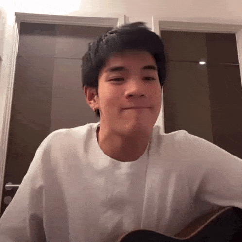 a man in a white shirt is playing a guitar