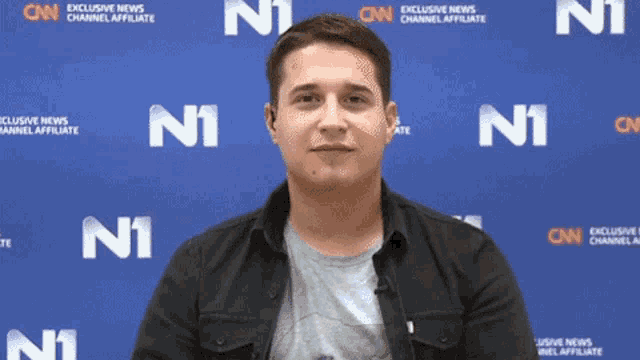a man stands in front of a blue wall that says cnn