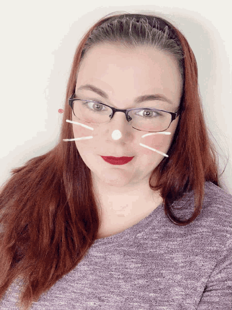 a woman wearing glasses has a cat face drawn on her nose