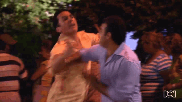 a man in a blue shirt is fighting another man in a yellow shirt in front of a crowd with a cn logo in the background