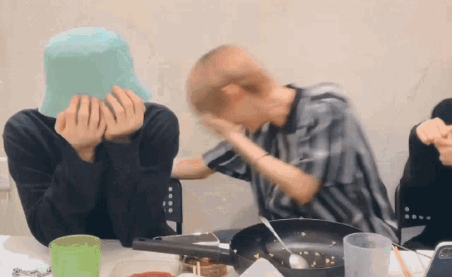a man in a blue hat is covering his face while another man holds his hand to his face