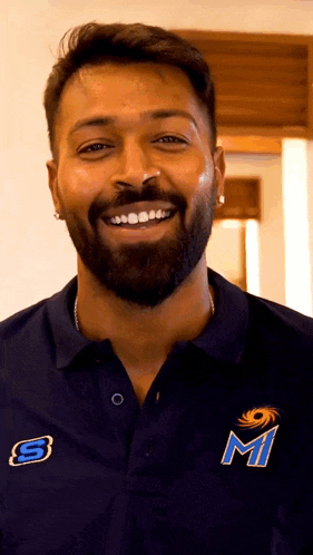 a man with a beard is wearing a blue shirt with the letter m on the front