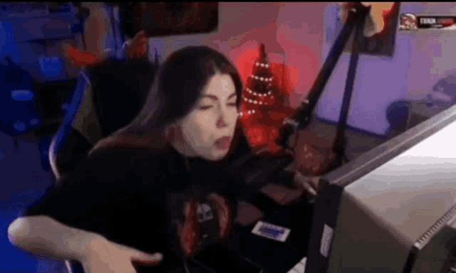 a woman is sitting in front of a microphone in front of a computer monitor .
