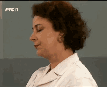 a woman with curly hair is wearing a white lab coat and earrings