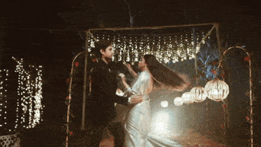 a bride and groom are dancing under a canopy with lights