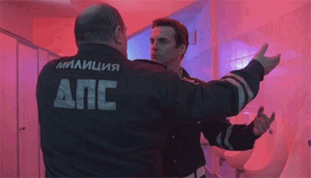 two police officers are hugging each other in a bathroom with a urinal
