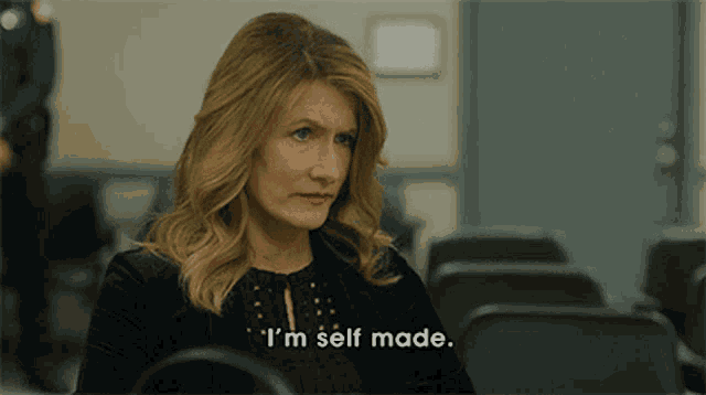 a woman sitting in a row of chairs with the words i 'm self made below her