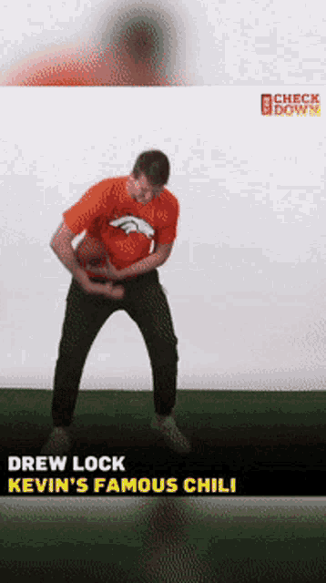 a man in an orange broncos shirt holds a football in his hands