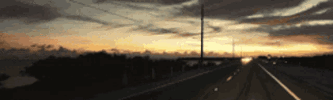 a blurry picture of a highway with a sunset in the background .