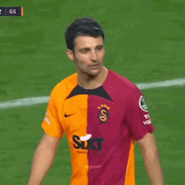 a soccer player wearing a red and orange shirt with sixt on the front