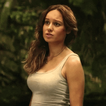 a woman in a tank top stands in a forest