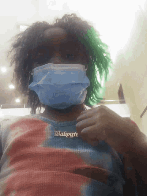 a person wearing a mask and a necklace with the word babygirl on it