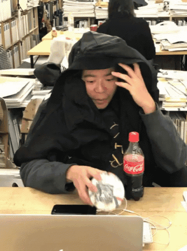 a person sitting at a desk with a bottle of coca cola on it