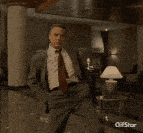 a man in a suit and tie is dancing in a hallway with the gifstar logo in the background