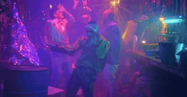 a group of people are dancing in a room with purple lights .