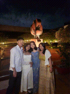 a group of people pose in front of a statue at night