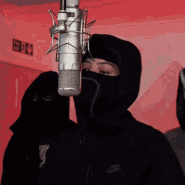 a man wearing a black nike jacket is standing in front of a microphone