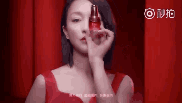 a woman in a red dress is holding a red bottle