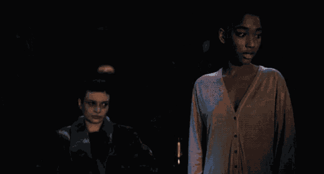 a woman in a cardigan is standing next to another woman in a fur coat