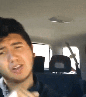 a man is sitting in the back seat of a car making a funny face