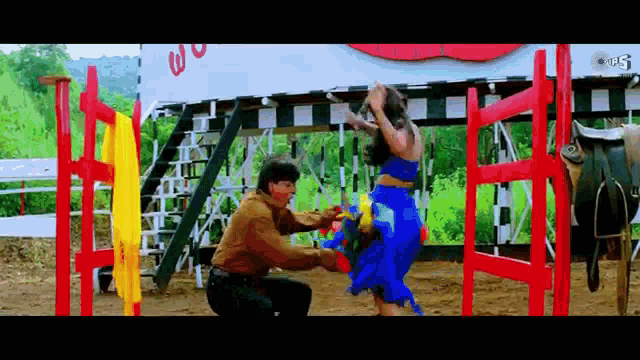 a man is kneeling down next to a woman in a blue dress