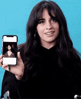 a woman is holding up a cell phone with a picture of a woman on it