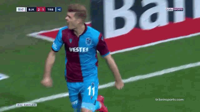 a soccer player celebrates a goal in front of a eko sign