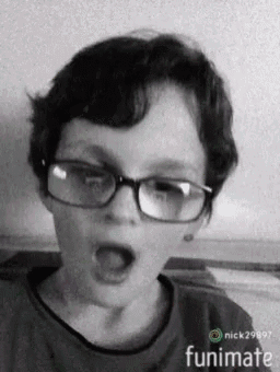 a black and white photo of a young boy wearing glasses with his mouth open