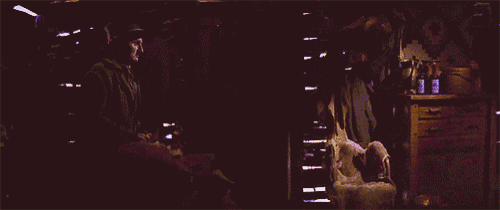 a man in a cowboy hat stands in a doorway in a dark room