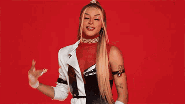 a woman in a red and white outfit is dancing on a red background and smiling .