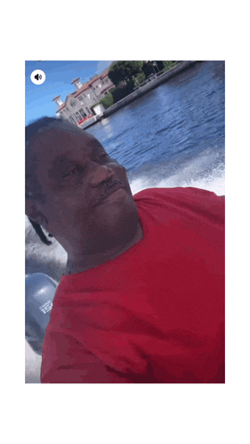 a man in a red shirt is riding a speed boat