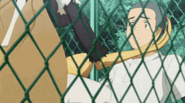 a man in a white shirt is behind a chain link fence looking at something