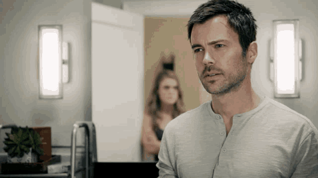 a man standing in front of a mirror with a woman behind him